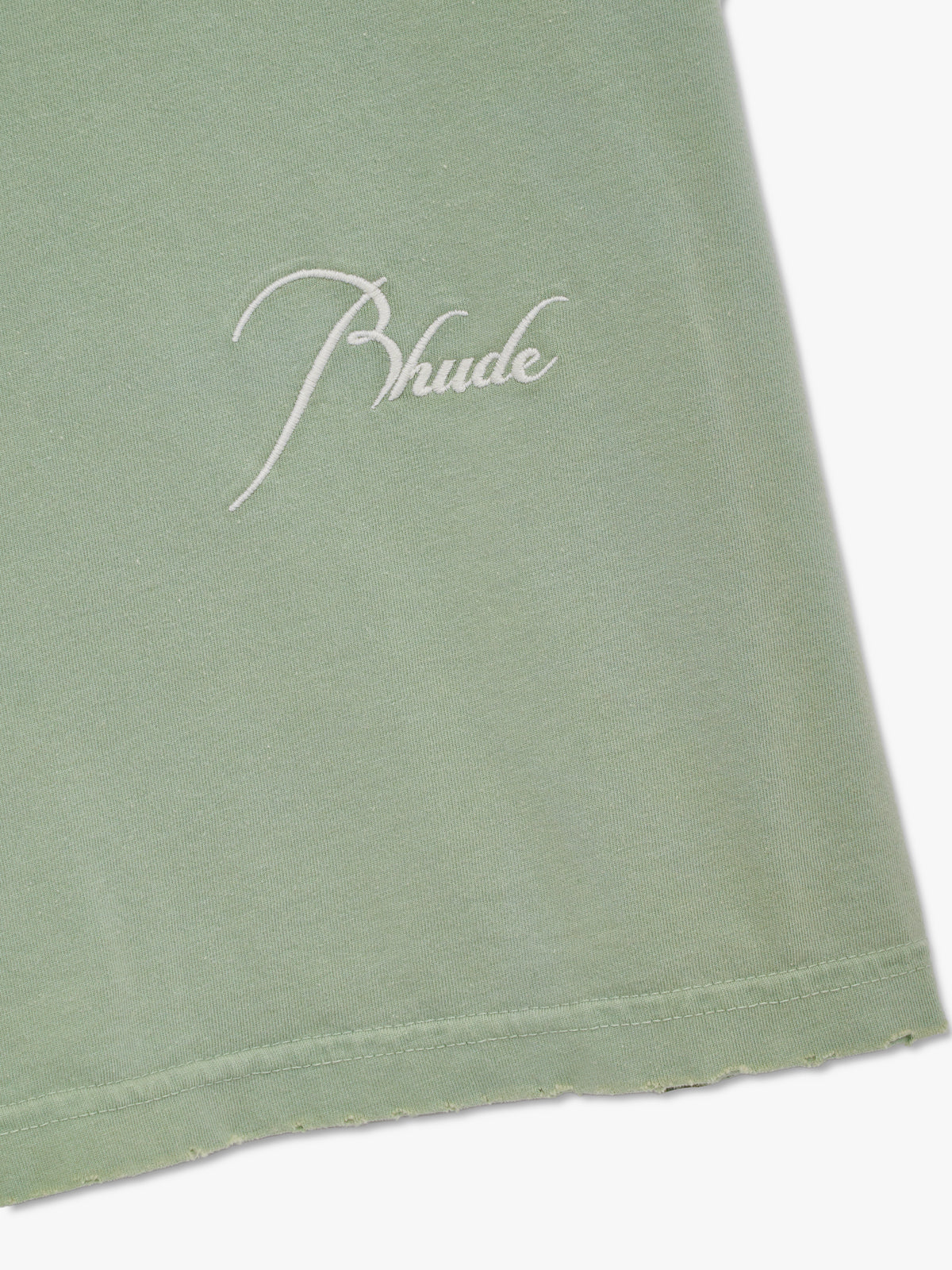 Close-up of the white script Rhude embroidery and frayed hem on the washed seafoam cutoff tee