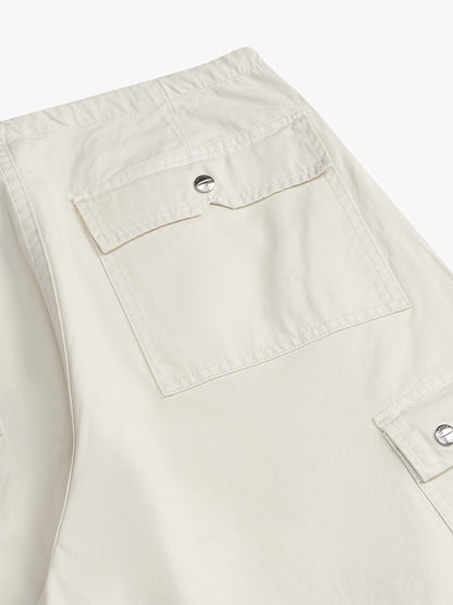 Close-up of the flap cargo pockets with metal snaps on the off-white washed parachute pants