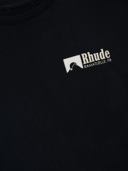 Close-up of the cream Rhude “Ramatuelle, FR” chest print with a rock silhouette square on the vintage black tee