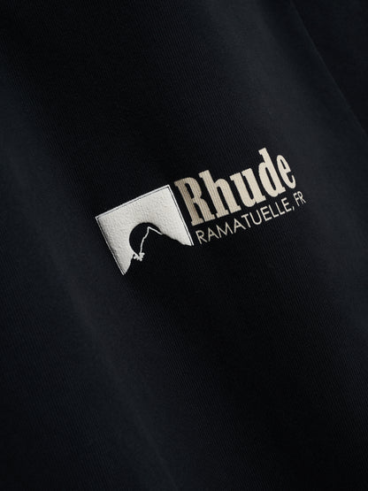 Angled close-up of the raised cream rock silhouette square and Rhude “Ramatuelle, FR” print on the vintage black tee