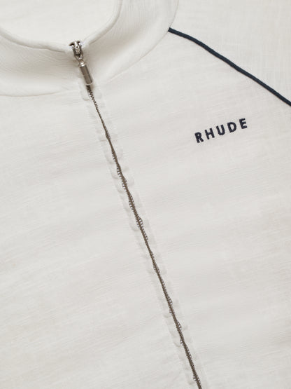 Close-up of the silver zip, stand collar and navy embroidered RHUDE chest logo on the white track jacket