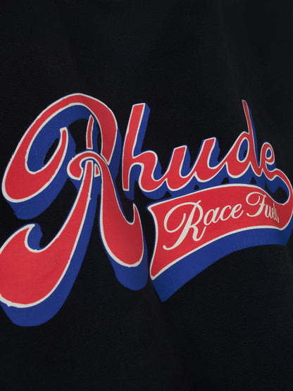 Angled detail of the red, blue and cream Rhude Race Fuels print on the vintage black hoodie