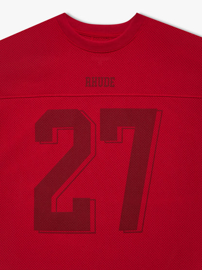 Close-up of the tonal RHUDE logo and number 27 below the collar of the red mesh football jersey