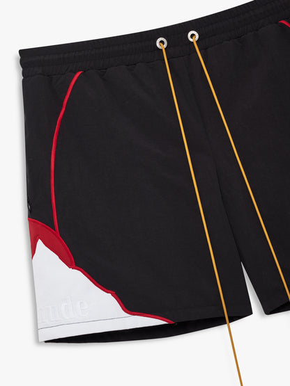 Angled close-up of the red piping, white mountain panel with tonal Rhude text and gold drawcords on the black shorts