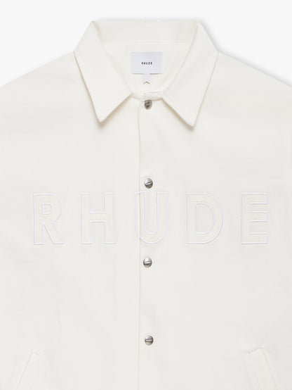 Close-up of the tonal white RHUDE embroidery, silver snaps and point collar on the white coaches jacket