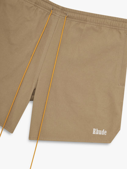 Angled close-up of the tan drawcords and white Rhude hem logo on the khaki twill shorts