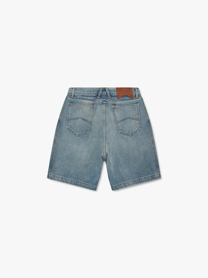Faded indigo boxy denim shorts with a brown Rhude waistband patch and chevron-stitched back pockets, back view