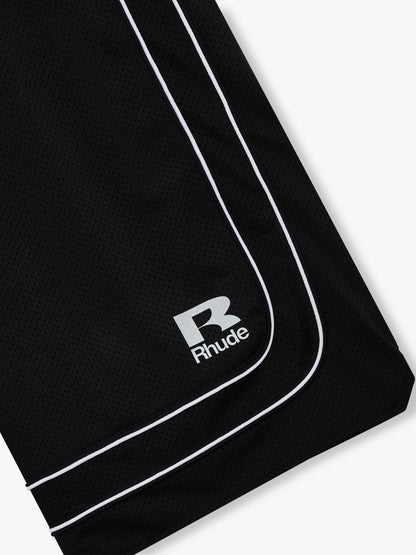 Close-up of the white R Rhude logo and curved double piping at the hem of the black mesh shorts
