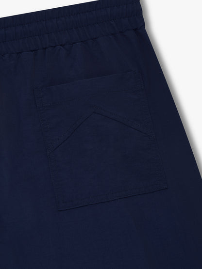 Angled close-up of the rear patch pocket below the elastic waistband on the navy track pants