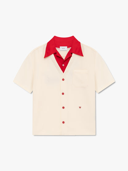 Cream bowling shirt with a red collar, red buttons, a chest pocket and a small red embroidered paisley motif, front view
