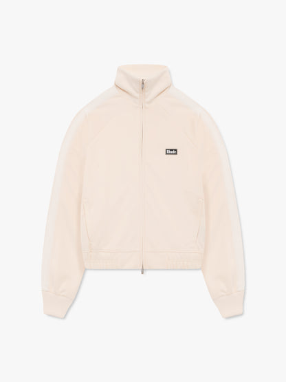 Cream track jacket with a stand collar, full zip, tonal sleeve stripes and a small black Rhude chest badge, front view