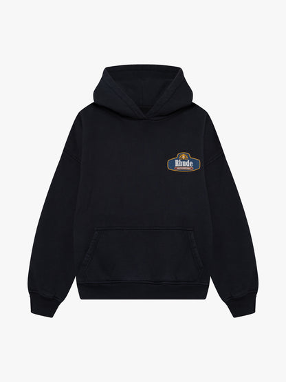 Black hoodie with a small blue Rhude Motorsport crest badge on the chest and a front pouch pocket, front view