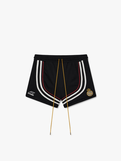 Black soccer shorts with curved white and red stripes, long gold drawcords, a RHUDE logo and gold crest, front view