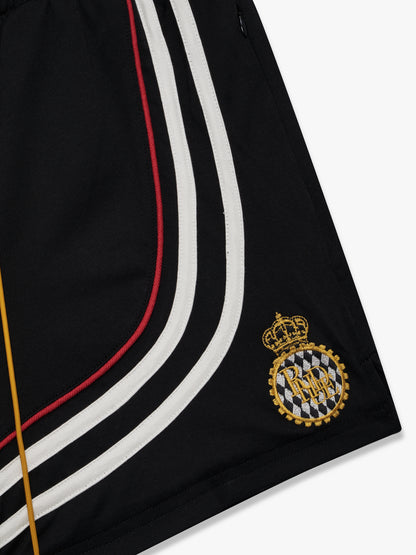 Close-up of the embroidered gold crown crest and curved stripes at the hem of the black shorts