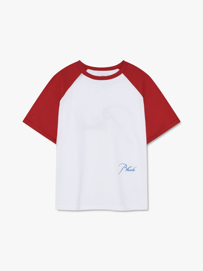 White raglan tee with red sleeves and small sky blue script Rhude embroidery near the hem, front view