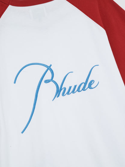 Close-up of the large sky blue script Rhude embroidery beside the red sleeve on the back of the raglan tee