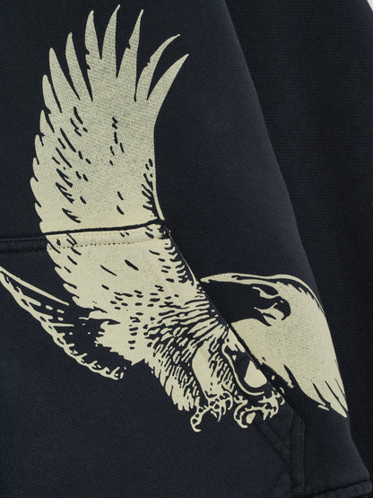 Close-up of the cream eagle print across the front pocket of the vintage black zip-up hoodie