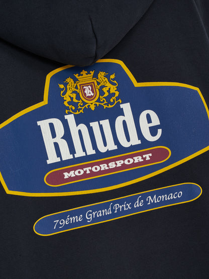 Close-up of the crowned R shield, gold lions and Rhude Motorsport lettering on the back of the vintage black zip-up hoodie
