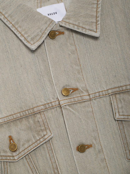 Angled close-up of the collar with a white RHUDE label, metal buttons and flap pocket on the liberty grey denim jacket