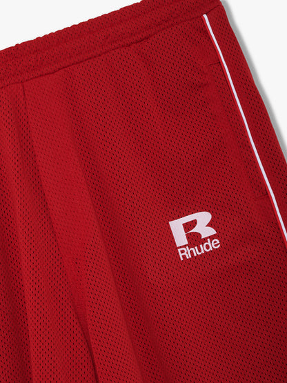 Close-up of the white R Rhude logo and side piping on the red mesh track pants