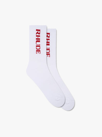 Pair of white ribbed crew socks with a vertical red RHUDE logo, front view