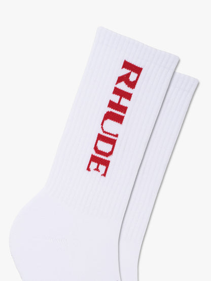 Close-up of the red knit RHUDE logo running down the white ribbed socks