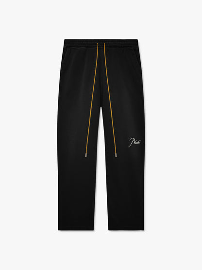 Washed black straight-leg sweatpants with long tan drawcords and white script Rhude embroidery on the leg, front view