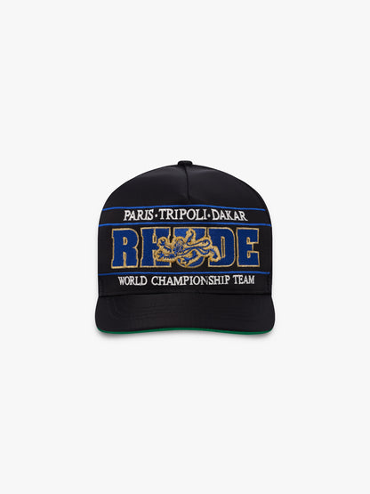Black cap with blue and gold RHUDE embroidery, “Paris Tripoli Dakar” and “World Championship Team” text, front view