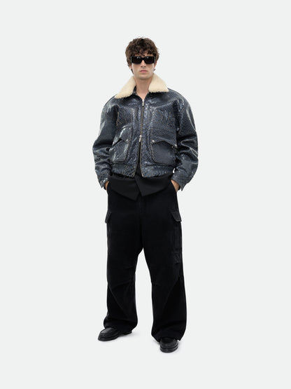 Model in sunglasses wearing the navy pilot jacket with hands in pockets and black cargo trousers, front view