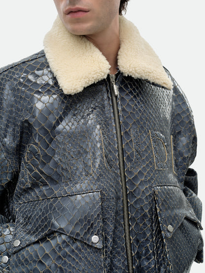 Close-up of the plush cream collar and tonal RHUDE lettering across the chest of the navy crocodile-textured jacket