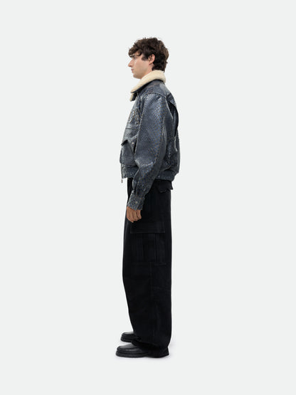 Model wearing the navy crocodile-textured pilot jacket with black cargo trousers, side view