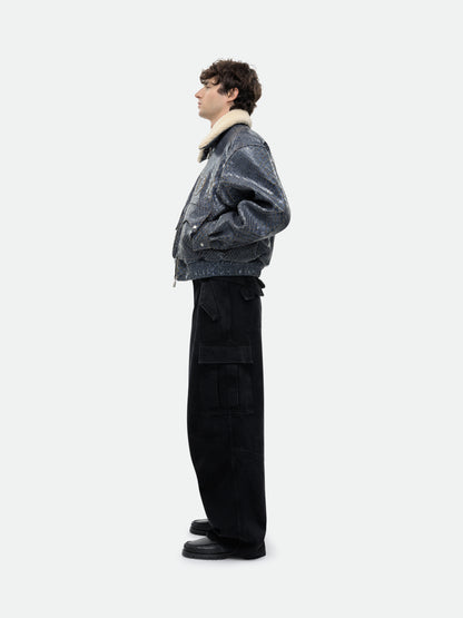 Model wearing the navy crocodile-textured pilot jacket with a hand in the pocket, side view