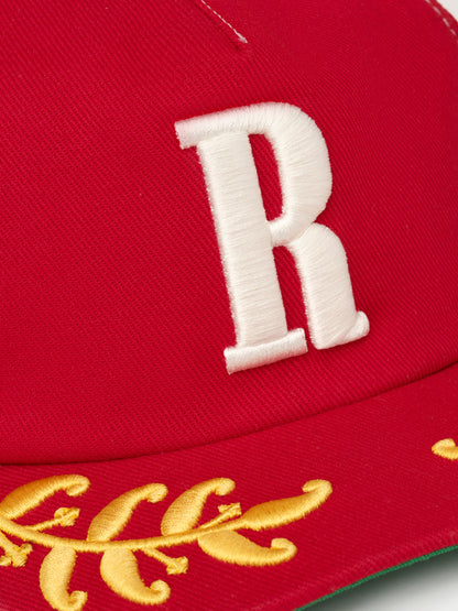 Close-up of the raised white R embroidery above the gold laurel brim on the red cap