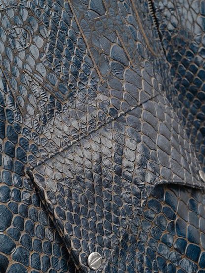 Detail of the navy crocodile-textured surface and snap pocket flap on the pilot jacket