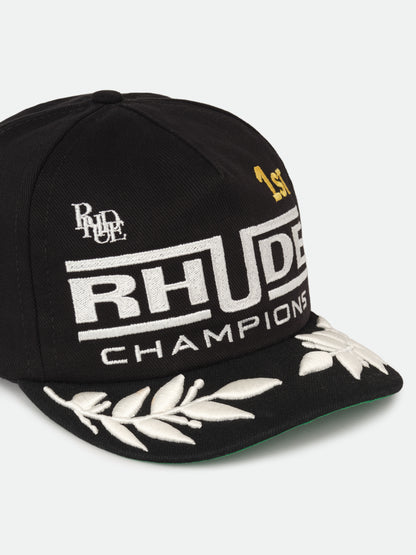Black Champions cap with a RHUDE monogram, white laurel brim embroidery and green underbrim, three-quarter view