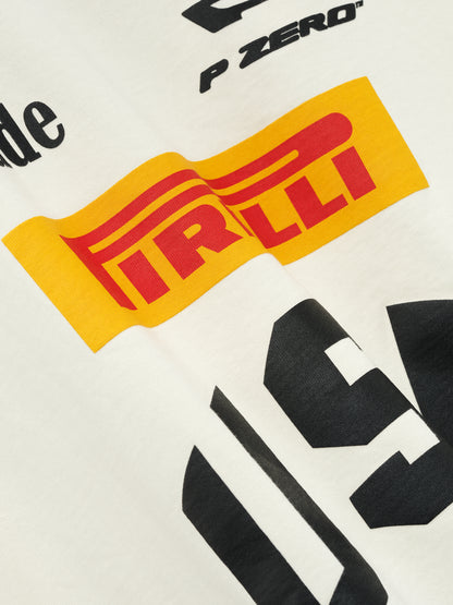 Angled close-up of the cracked yellow Pirelli logo and black “USA” lettering on the vintage white tee