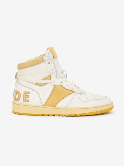 White and mustard high-top sneaker with an ankle strap, mustard side panel and RHUDE lettering at the heel, side view